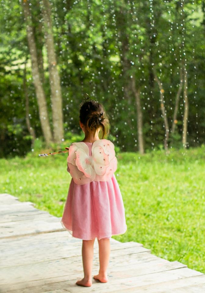 Ein Mädchen im rosa Kleid mit Schmetterlingsflügeln.