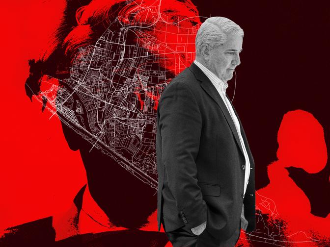 Bezirksvorsteher Ernst Nevrivy während seinem Prozess im Anzug steht mit den Händen in den Taschen vor einem roten Hintergrund mit der Karte von Donaustadt und einer Silhouette.