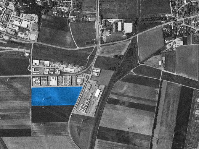 Luftbild einer städtischen und landwirtschaftlichen Umgebung mit einem blau hervorgehobenen Bereich in der Mitte der Aufnahme.
