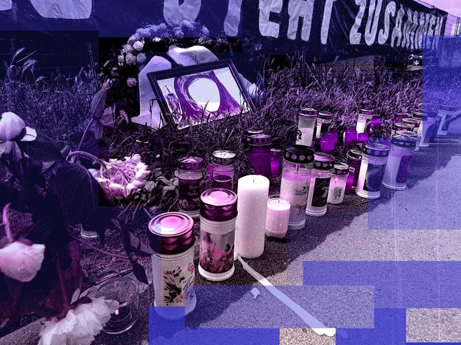 Kerzen und Blumen, die auf dem Boden als Gedenkstätte arrangiert sind, mit einem gerahmten Foto und einem teilweise sichtbaren Banner im Hintergrund.