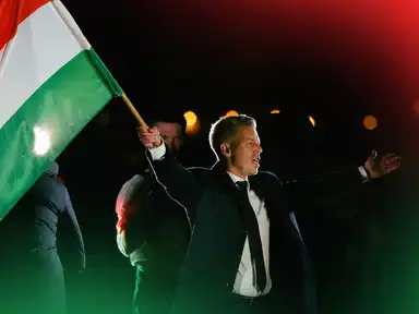 Peter Magyar, Vorsitzender der oppositionellen Tisza-Partei, schwenkt jubelnd eine ungarische Flagge, nachdem der ungarische Ministerpräsident Viktor Orbán seine Niederlage bei den Parlamentswahlen eingestanden hat, in Budapest, Ungarn, am 12. April 2026.