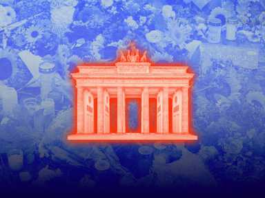 Das Brandenburger Tor in Rot leuchtet auf einem blau getönten Hintergrund mit Blumen und Kerzen.