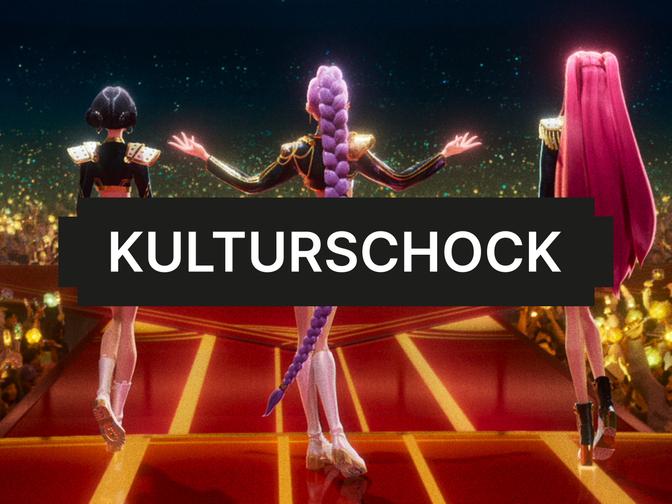 Drei animierte Figuren mit bunten Haaren stehen auf einer Bühne vor einem Publikum. Der Text "KULTURSCHOCK" ist im Vordergrund sichtbar.