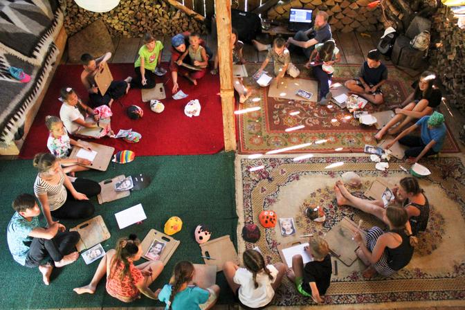 Die Kinder sitzen im Kreis und arbeiten mit Fotos und Masken