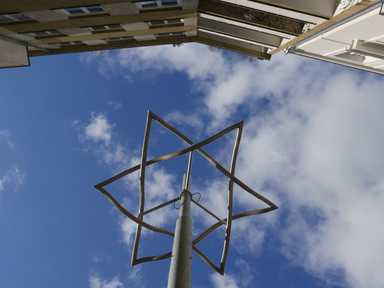 Ein Davidstern aus Metall vor blauem Himmel in der Siebenbrunnengasse