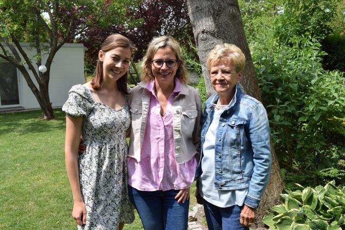 Drei Frauen unterschiedlicher Generation stehen im Garten.