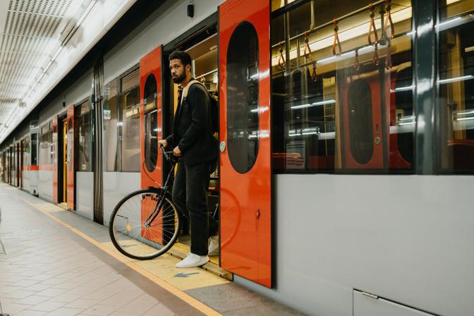 Mann mit Fahrrad in einer U-Bahn-Station, beim Verlassen der U-Bahn. Alleinstehender Mann, der mit öffentlichen Verkehrsmitteln und seinem Fahrrad durch die Stadt fährt. Nachhaltiger Lebensstil eines alleinstehenden Mannes.